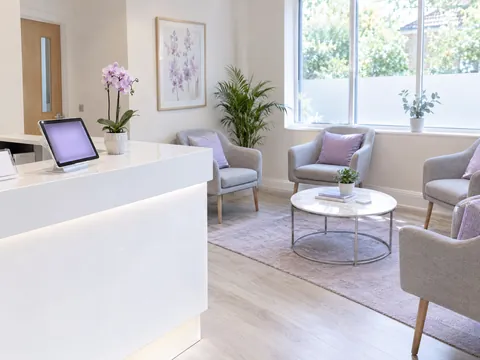 A clinic’s reception and waiting room, with Evrella answering on the tablet at the front desk